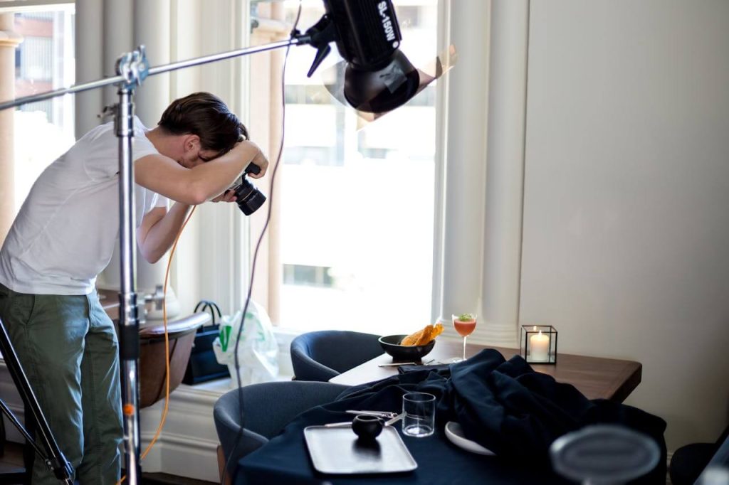 Man Taking Photo of Items on Table